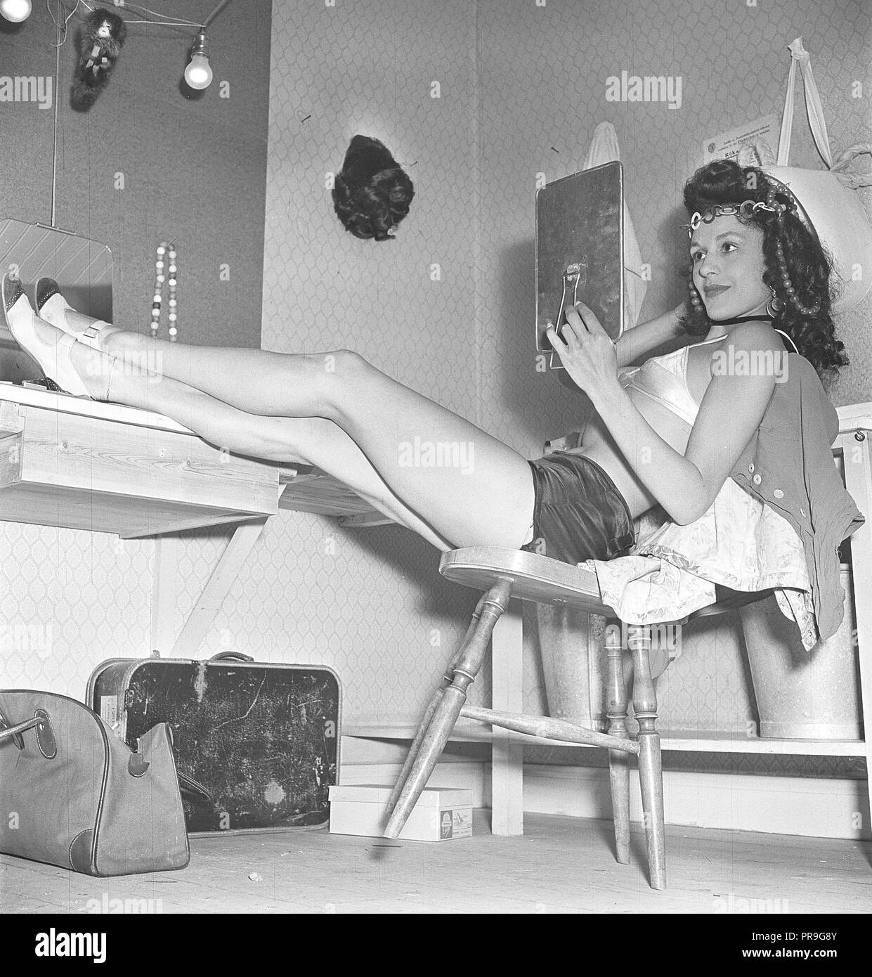 Fille de ballet dans les années 1940. La jeune fille se prépare pour théâtre performance tonights back stage, et est assis dans le vestiaire, reposant ses longues jambes, et est à la recherche dans le miroir. Il est vêtu d'un costume deux pièces. Suède 1946. Kristoffersson Photo AC72-4 Banque D'Images