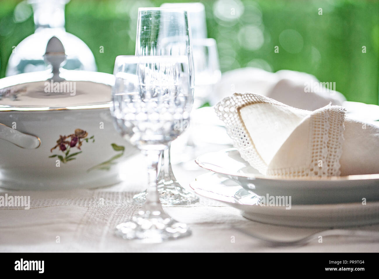 Manger amende : blanc motif floral de Chine dîner organisé sur une table avec nappe vintage et napikins, verres en cristal. Focus sélectif. Banque D'Images