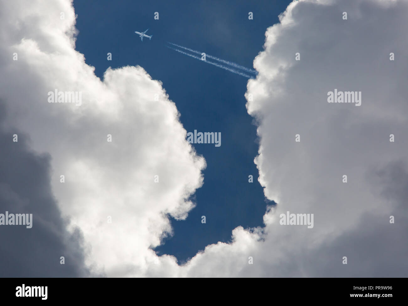 Un avion volant à haute altitude dans un ciel bleu profond au-dessus des nuages d'orage menaçant. Banque D'Images