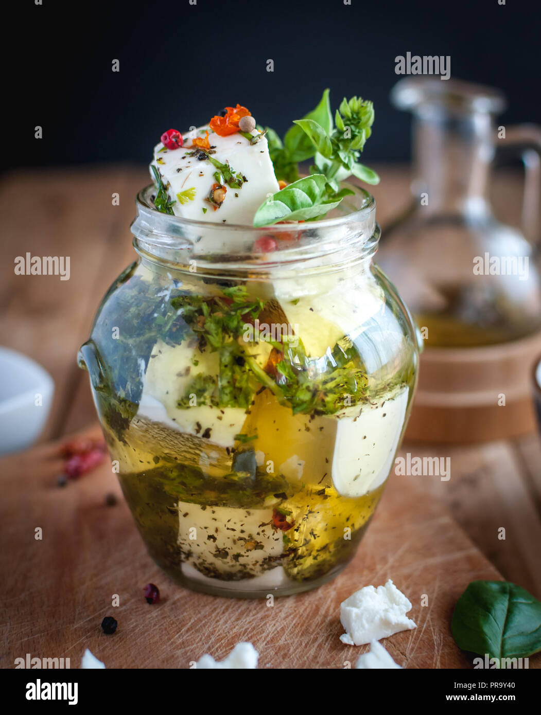 Close-up de Feta mariné dans l'huile d'olive, les herbes et les flocons de poivron rouge sur fond de bois Banque D'Images