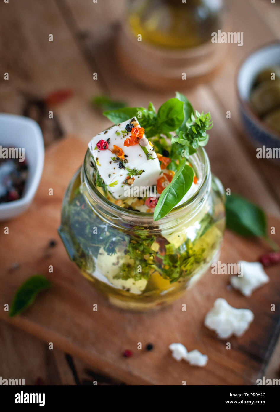 Close-up de Feta mariné dans l'huile d'olive, les herbes et les flocons de poivron rouge sur fond de bois Banque D'Images