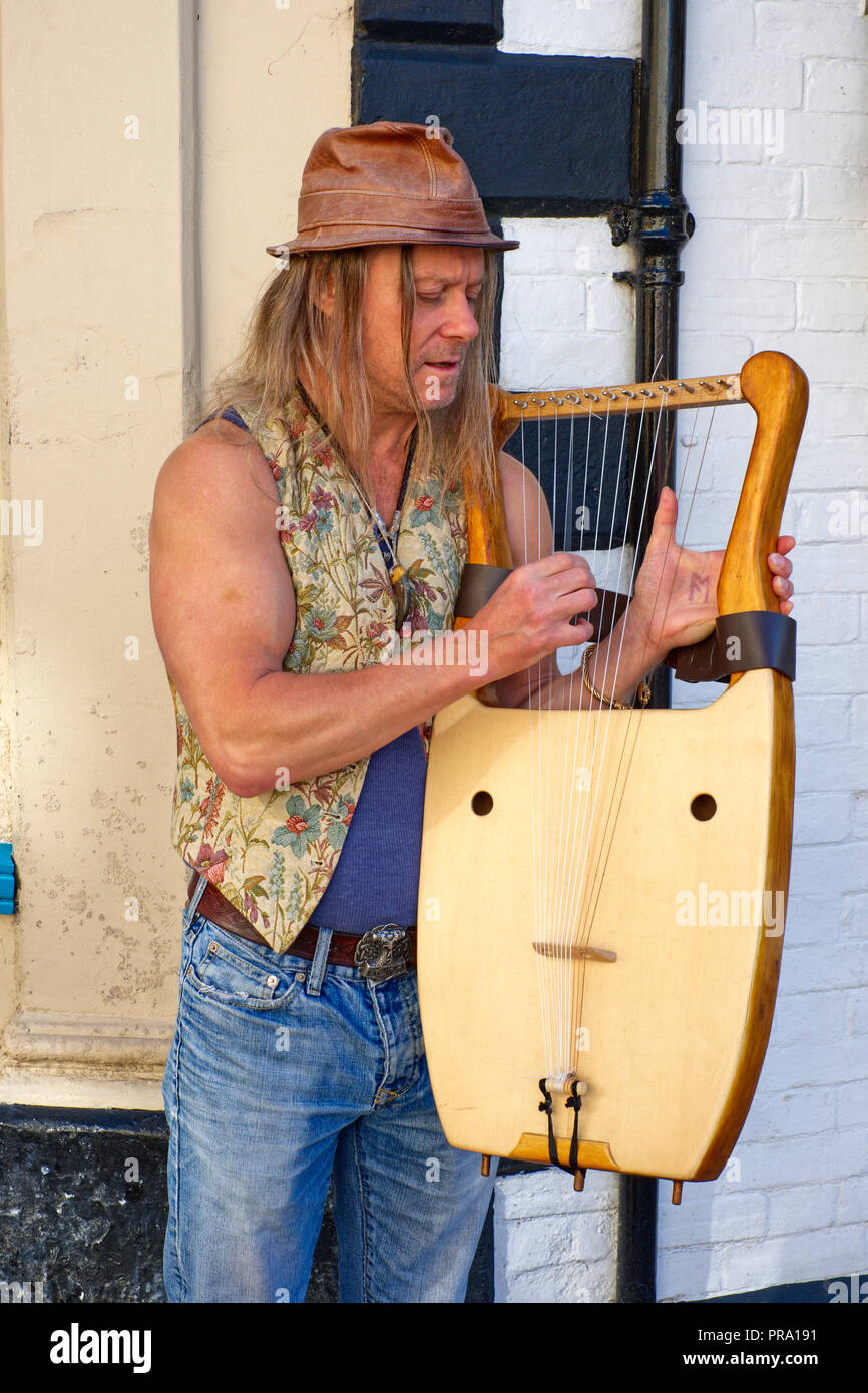 Musicien jouant une lyre sur la rue principale à Glastonbury, Somerset, UK Banque D'Images