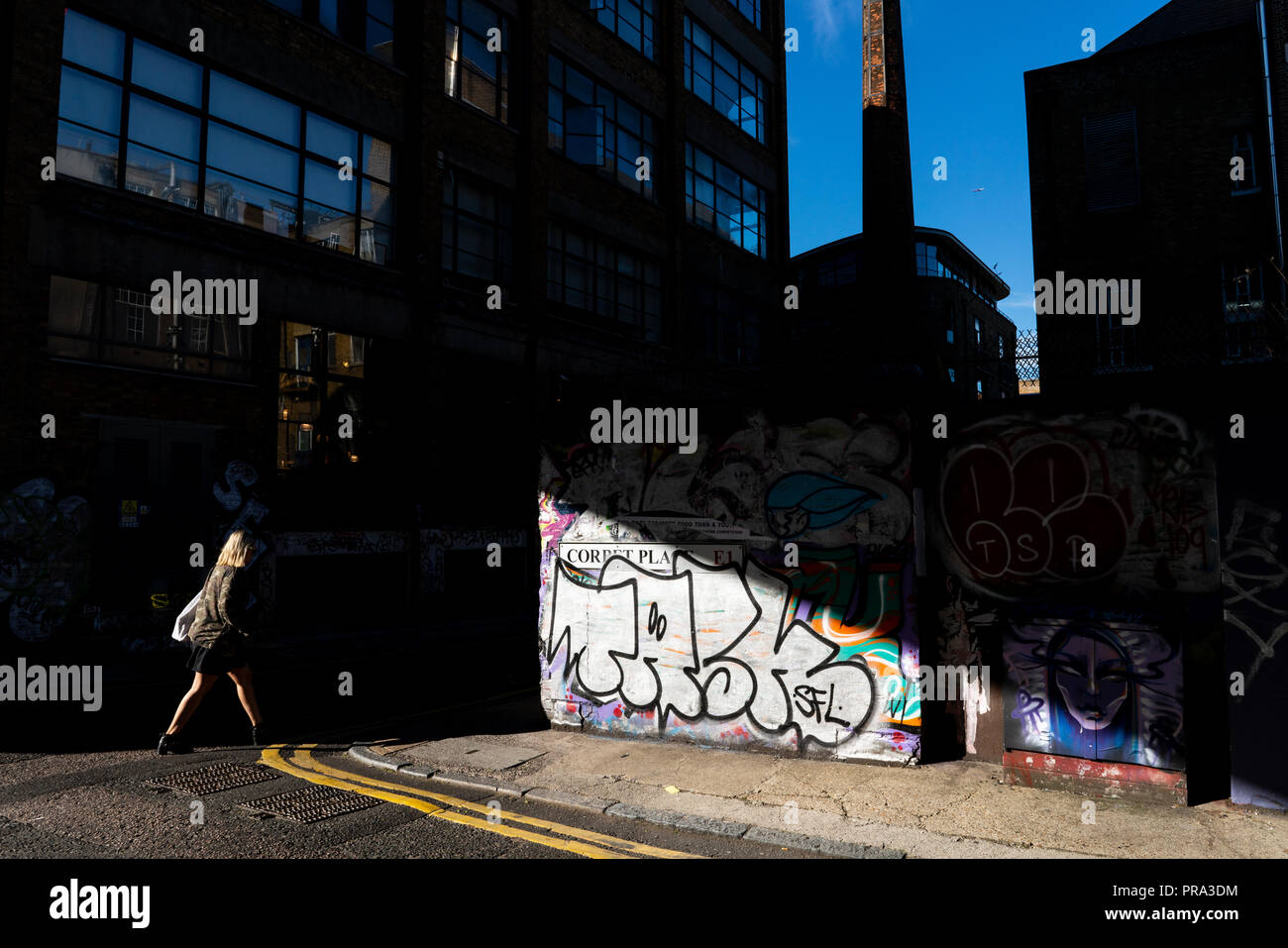 Toujours soleil bas. Il s'en composition. Dans cette image d'une femme fait son chemin le long d'une rue de Shoreditch, East London Banque D'Images