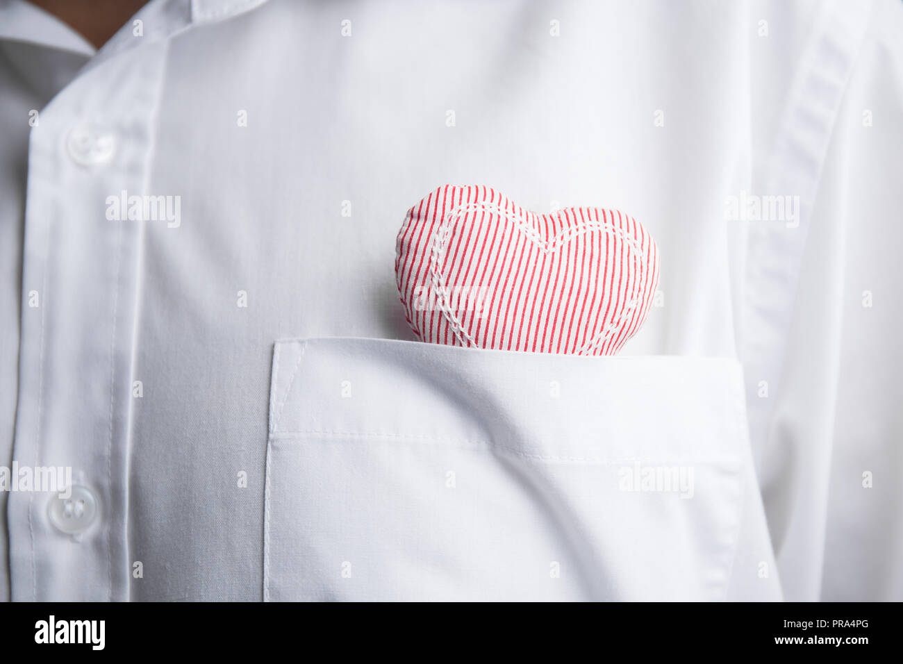 Coeur en tissu dans la poche d'une chemise. Banque D'Images