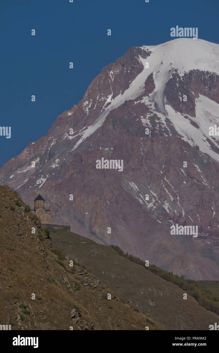 Vue de l'église Sainte trinité Gergeti par Chkheri la rivière, à une altitude de 2170 mètres, sous le mont Kazbegi, à une altitude de 2170 mètres dans la région de th Banque D'Images