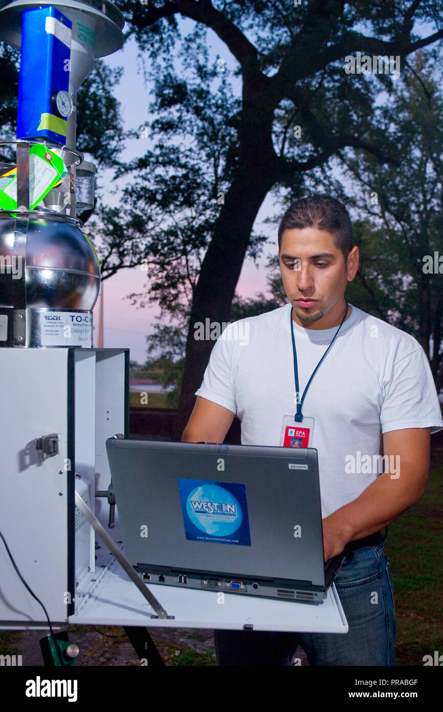 Un organisme de protection de l'environnement entrepreneur avec Weston, vérifie les Solutions installation de sampeling bollle de l'air sur le poste distant. Banque D'Images