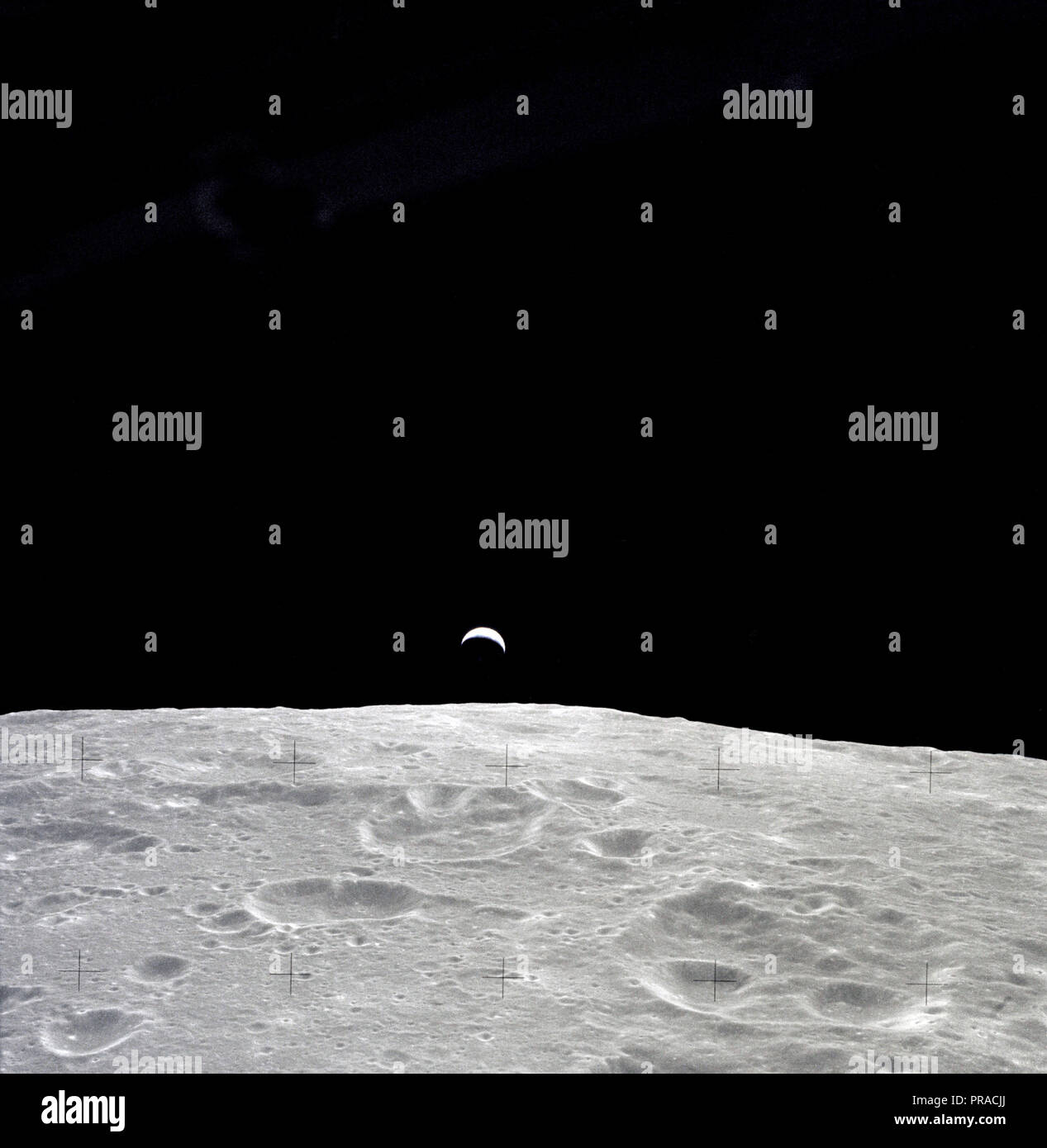 Une terre illuminée partiellement s'élève au-dessus de l'horizon lunaire dans cette photographie prise du vaisseau Apollo 12 en orbite lunaire. Banque D'Images