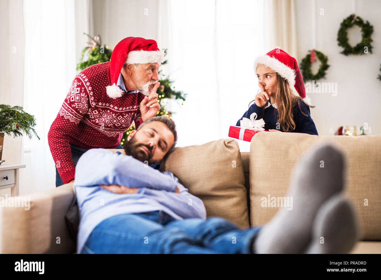 Une petite fille avec son grand-père ne veulent pas se réveiller du sommeil de son père à l'époque de Noël. Banque D'Images