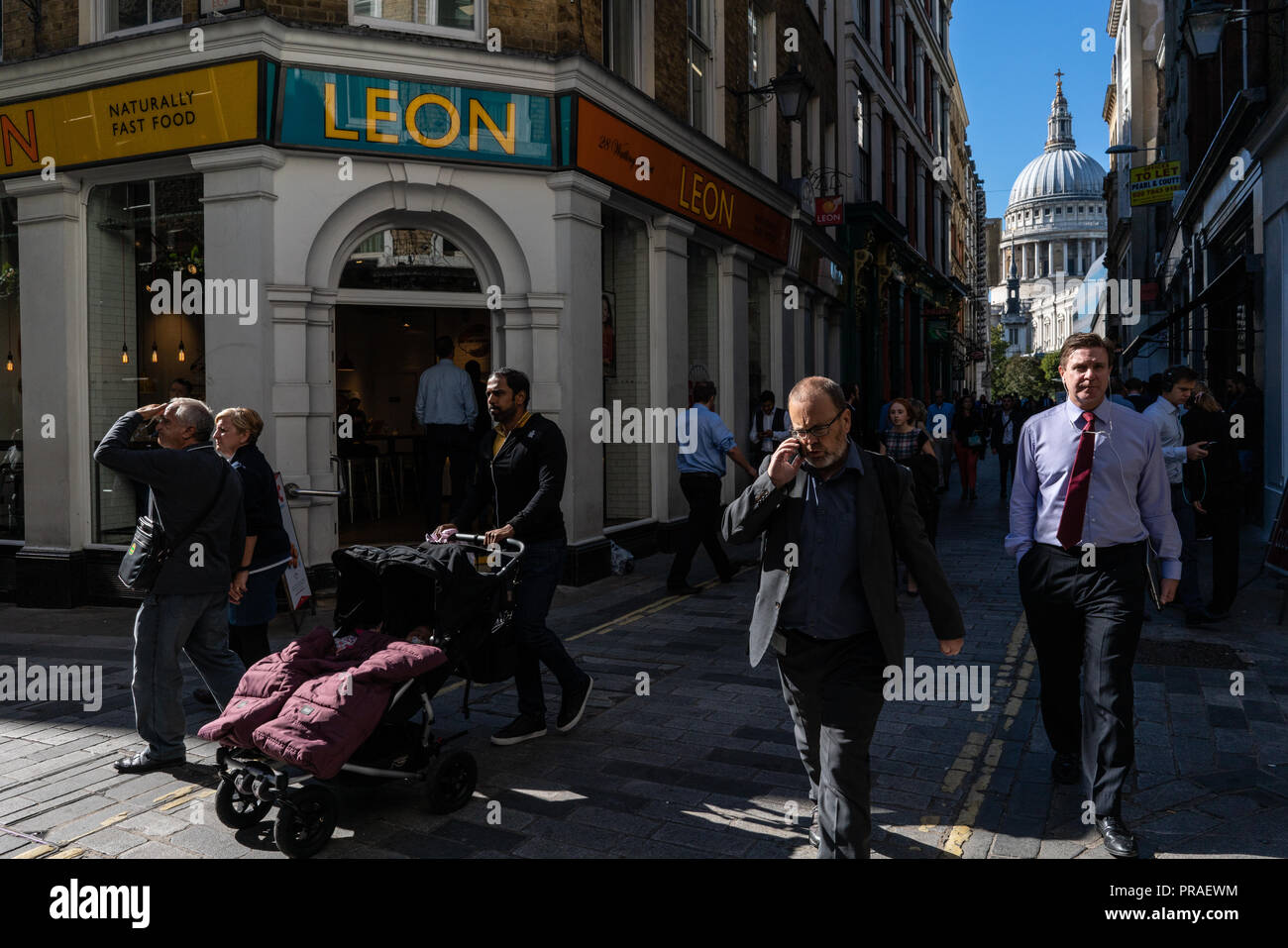 Scène de rue général des travailleurs de la ville de Londres s'occuper de leurs affaires pendant leur pause déjeuner près de la Cathédrale St Paul London UK Banque D'Images