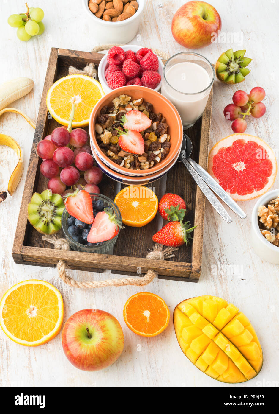 L'écrou et de grain paléo granola aux fruits servi avec des fruits et petits fruits, lait noix, vertical, vue de dessus, selective focus Banque D'Images