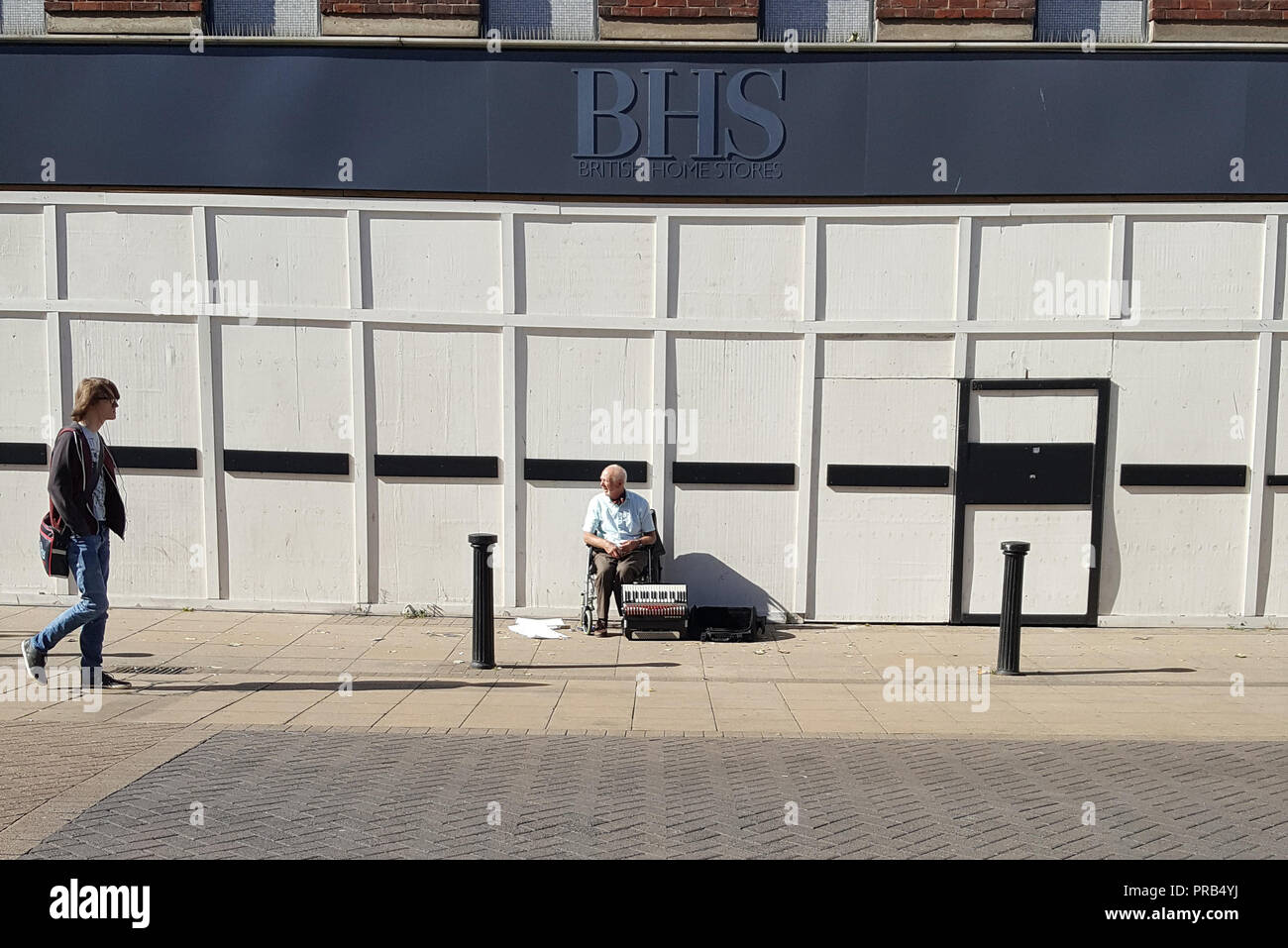 La photographie de rue d'un musicien ambulant en dehors de la maintenant fermée de l'intérieur britannique de la direction générale des magasins de Lincoln, Royaume-Uni Image prise sur un smartphone. Banque D'Images