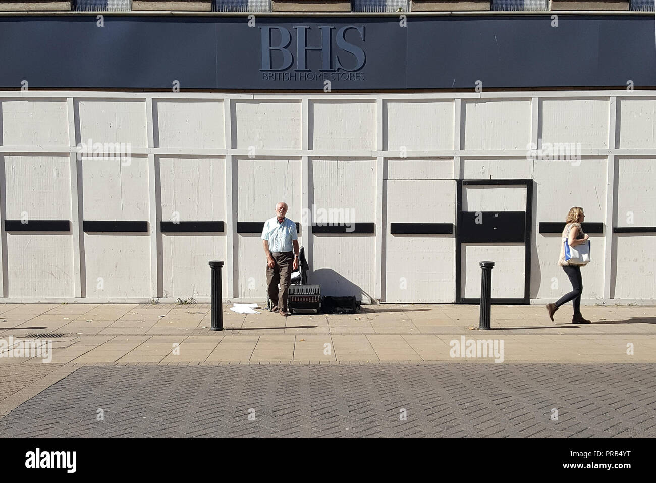 La photographie de rue d'un musicien ambulant en dehors de la maintenant fermée de l'intérieur britannique de la direction générale des magasins de Lincoln, Royaume-Uni Image prise sur un smartphone. Banque D'Images