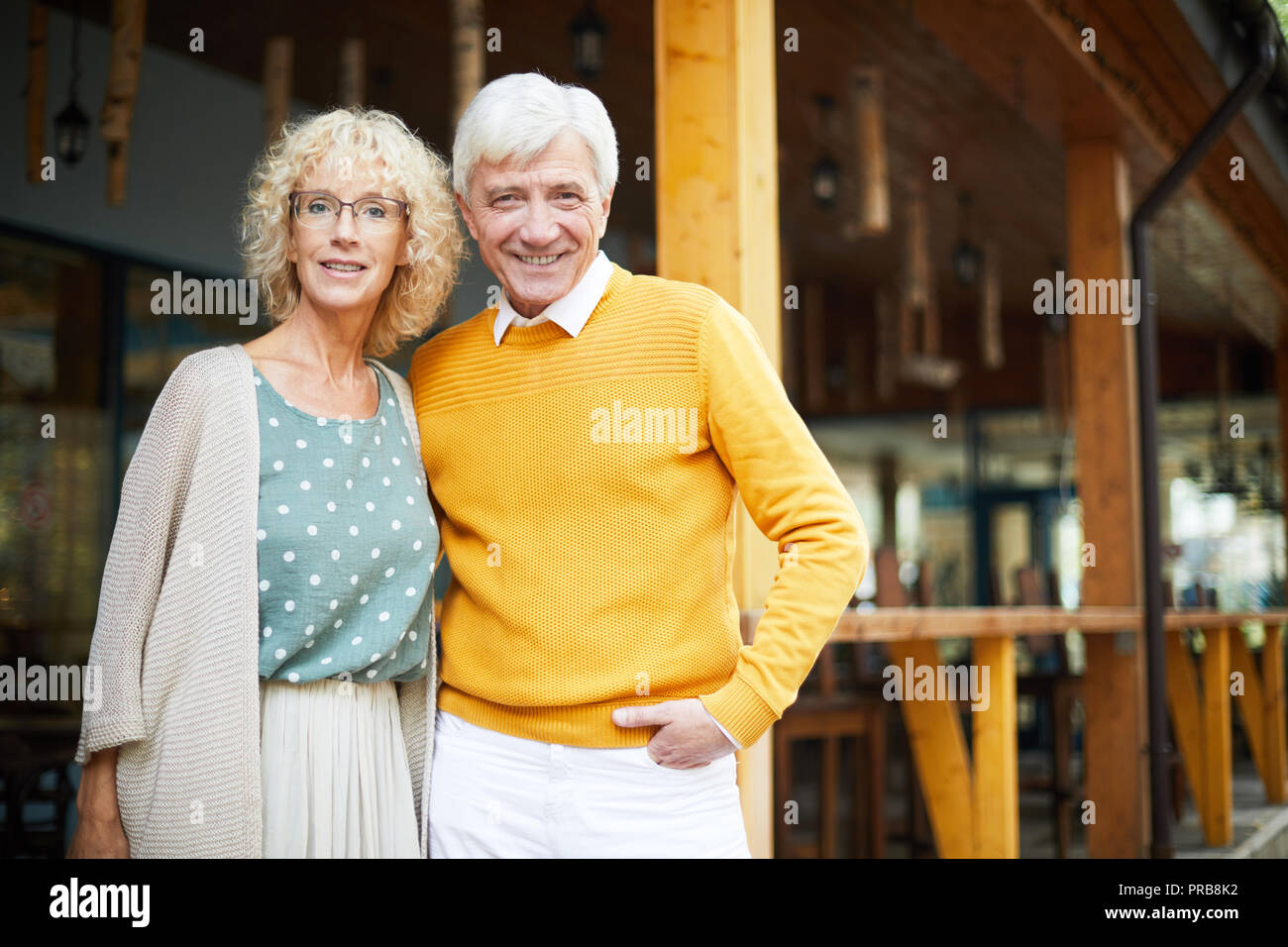 Smiling couple à la mode et véranda looking at camera, bel homme embrassant petite amie dans les verres Banque D'Images