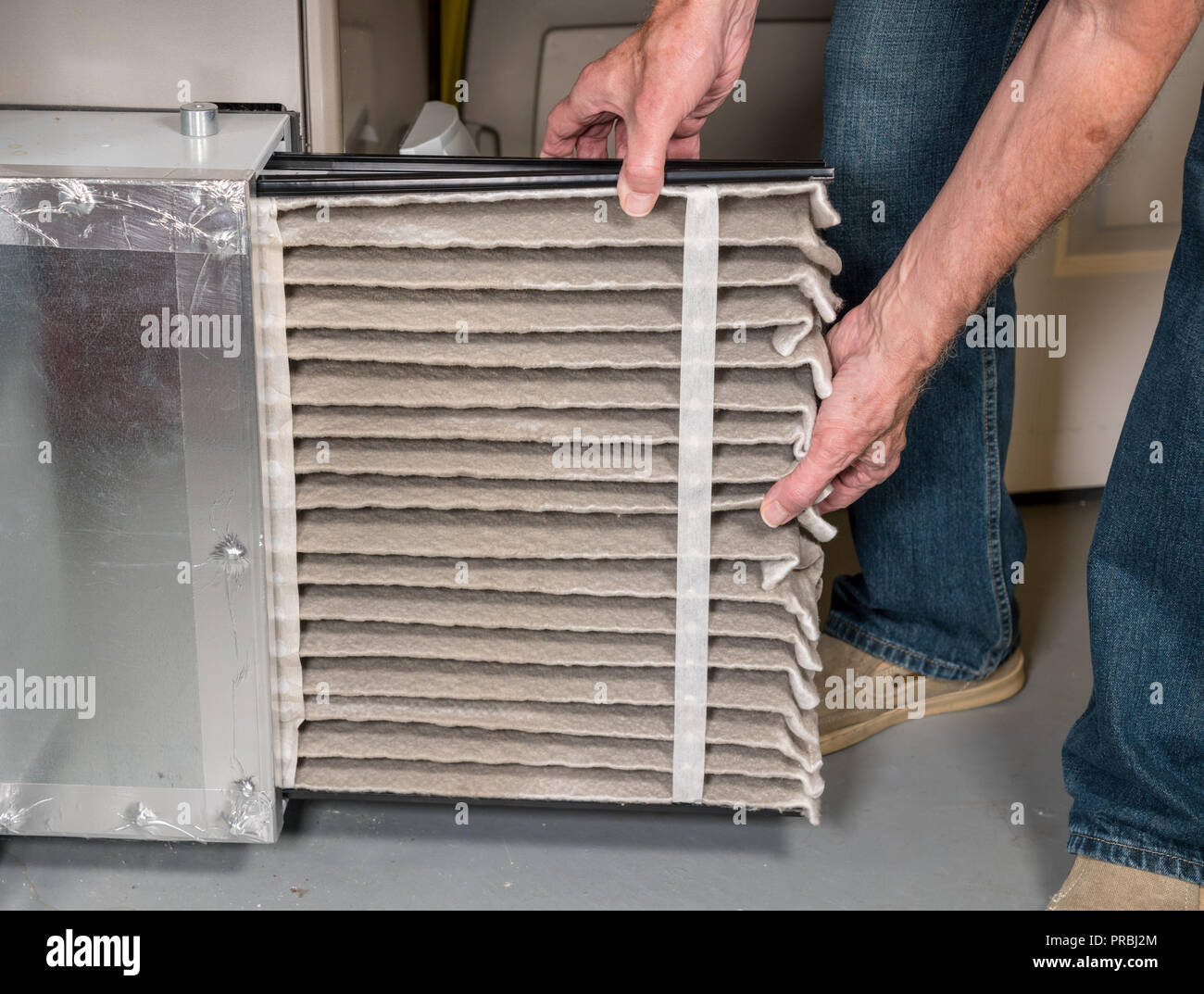 Man de changer un filtre à air encrassé dans un four de chauffage-climatisation Banque D'Images