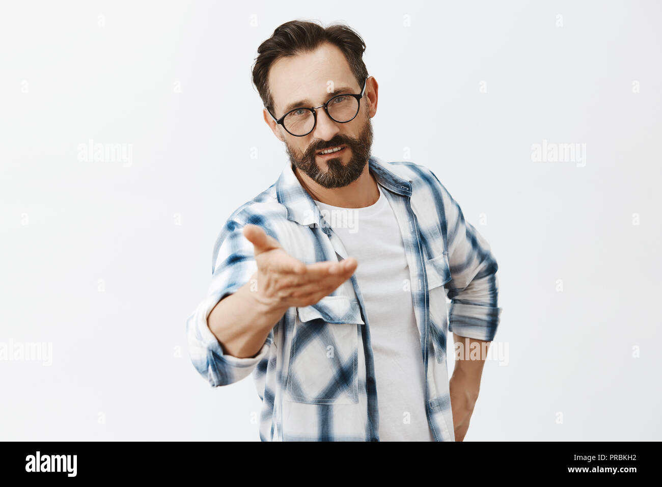 Votre point de vue. Portrait of handsome man cool et confiante avec les rides et barbe, tirant part vers la caméra comme si quelqu'un du doigt tout en donnant la parole, tenant le bras sur la taille Banque D'Images