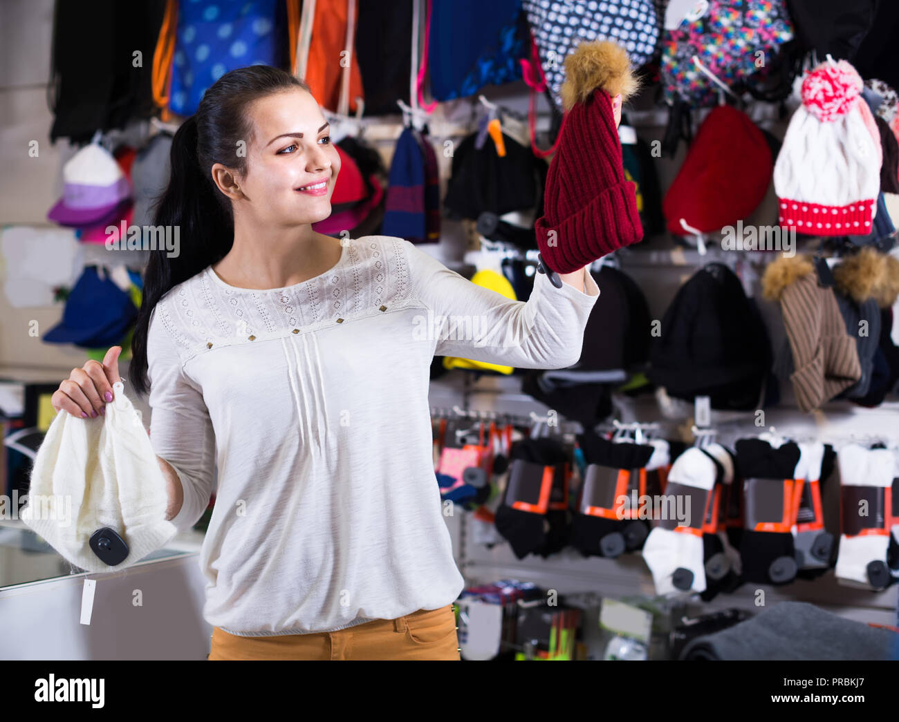 American girl Smiling décider sur chapeau chaud dans magasin de sport Banque D'Images