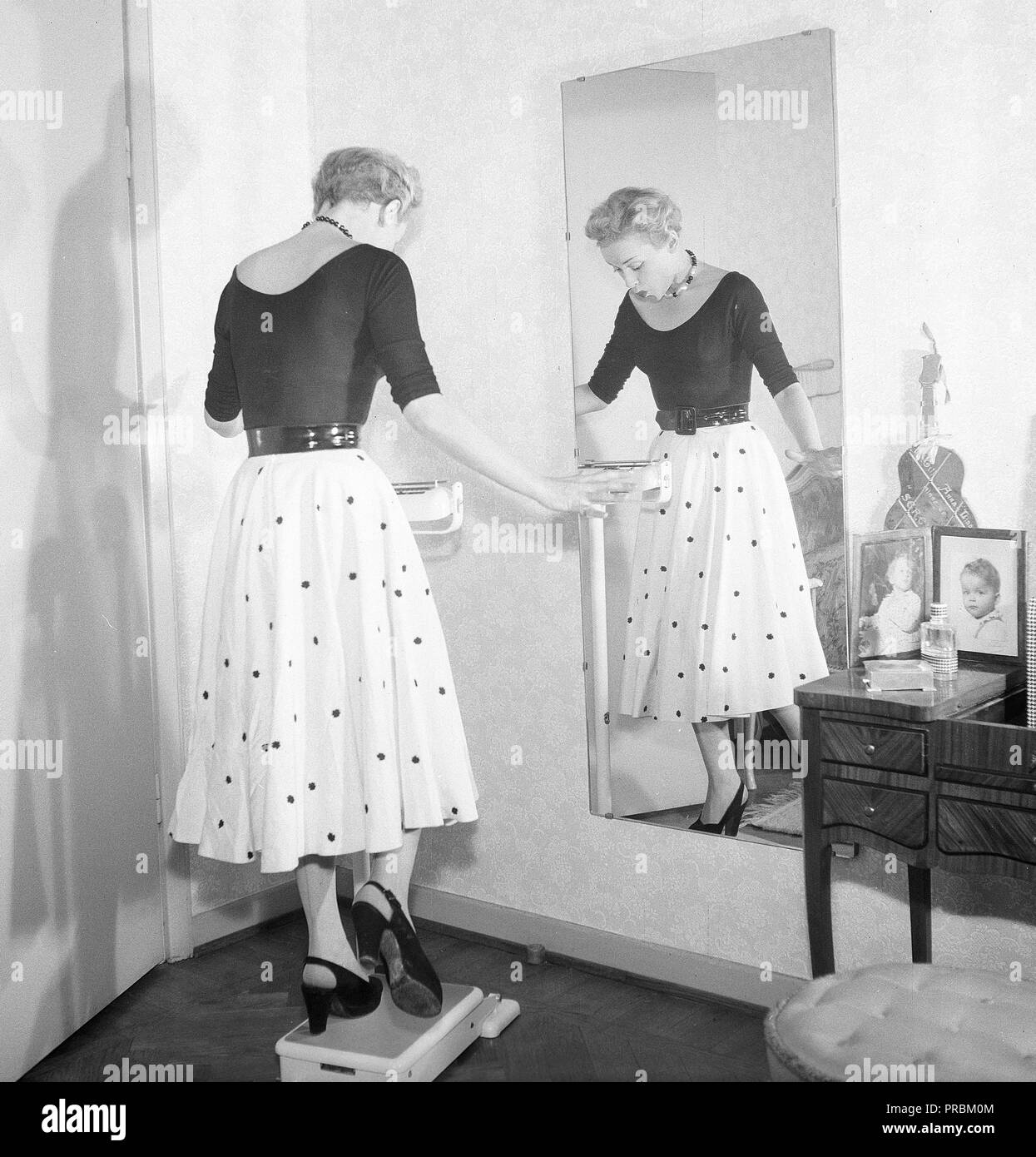 La mode des années 1950. Une jeune femme se tient debout sur une jambe sur l'échelle d'essayer d'être aussi léger que possible. Actrice photos AnnaLisa Ericson, 1913-1911. La Suède des années 1950. Kristoffersson Photo ref BM74-10 Banque D'Images