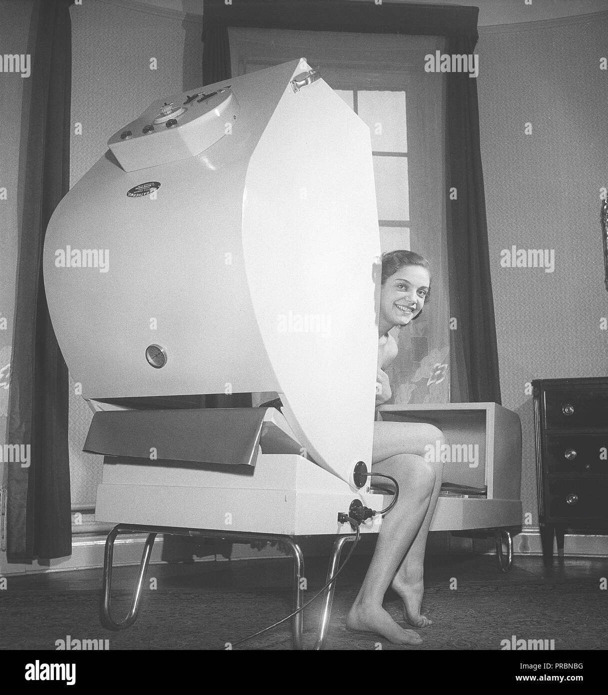 Soins de beauté en 1950s. Une jeune femme est assise dans une machine nommée Infra Thermo. Un traitement dans la machine soulage la douleur par les vagues de chaleur. Suède 1951. Photo Kristoffersson Réf. BB81-9 Banque D'Images