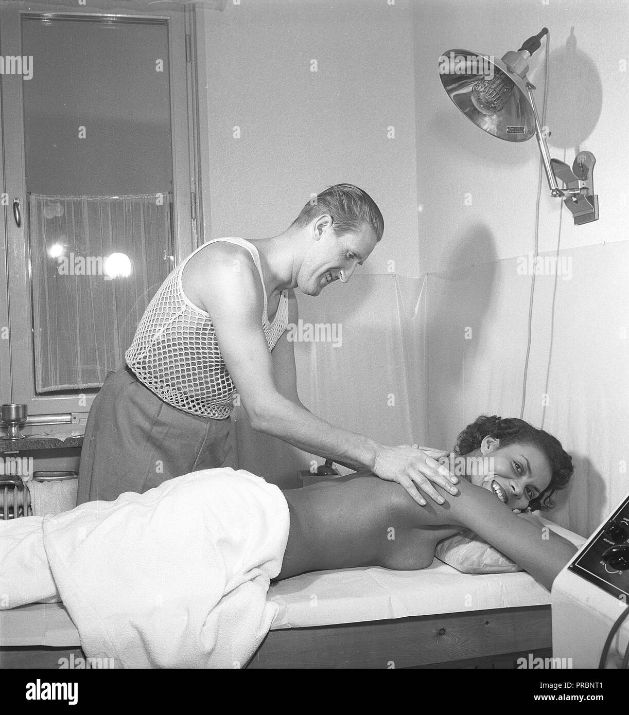 Soins de beauté dans les années 1950. Une jeune femme est d'avoir un massage par un homme de la manipulation du traitement. Il porte la sorte très spéciale de t-shirt avec le tricot comme un filet, principalement pour être utilisée sous votre chemise. Suède 1951. Kristoffersson Photo Ref ÊTRE103-3 Banque D'Images