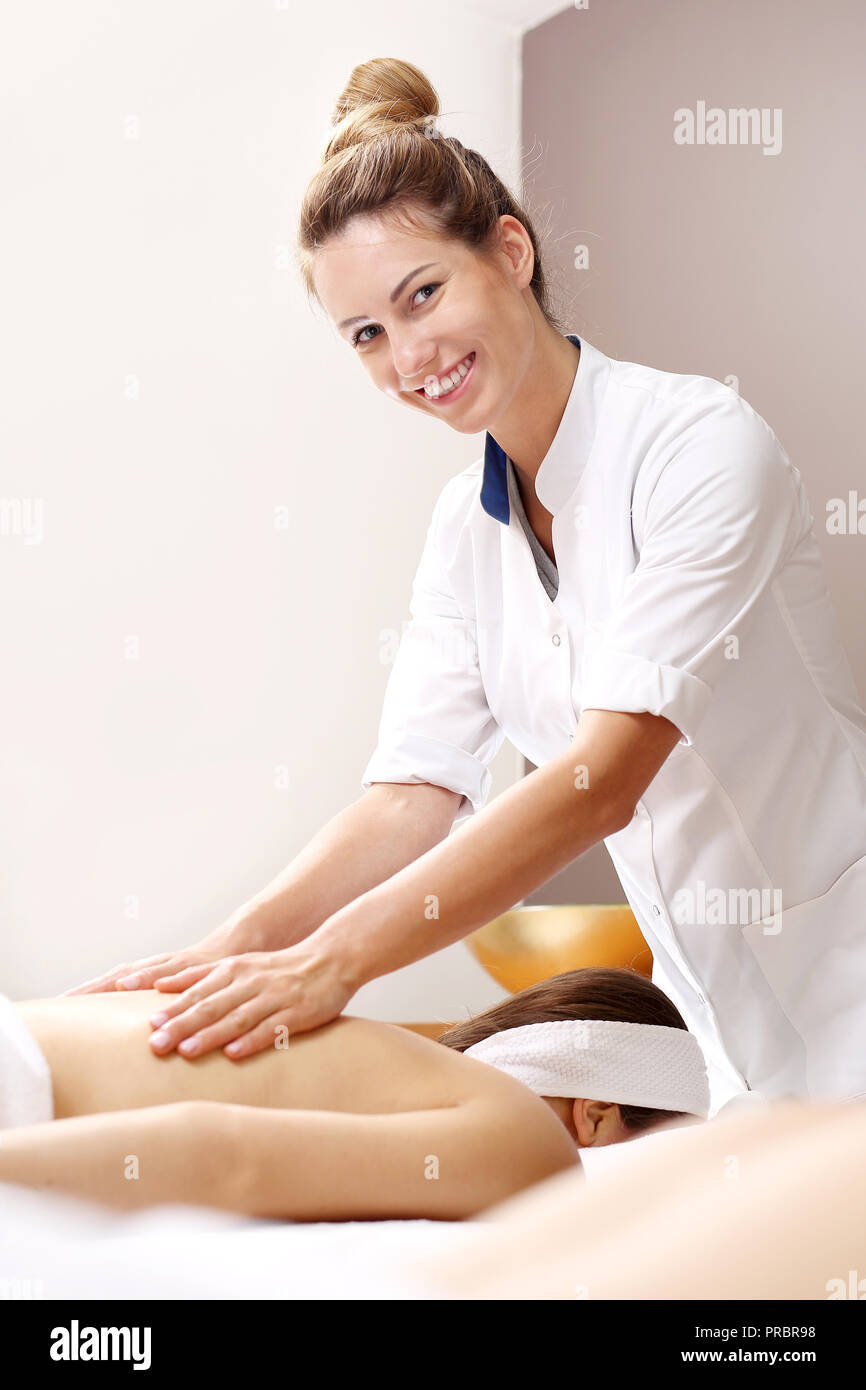 Massage du dos avec des huiles. Masseuse en ajoutant de l'huile au dos. Banque D'Images