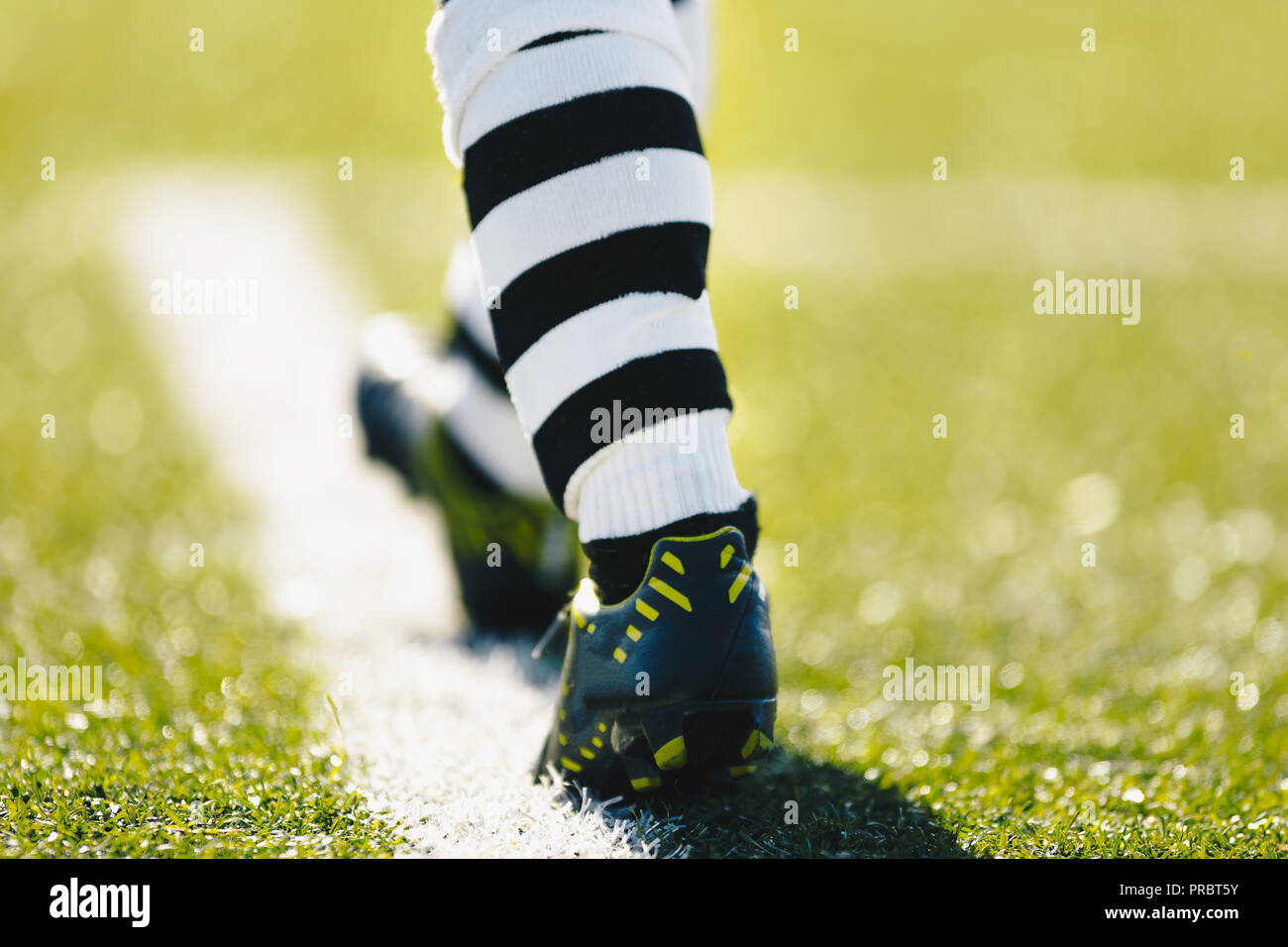Les jambes d'un joueur de football. Joueur de football sur un terrain  d'herbe. Joueur de football en crampons et chaussures de football  professionnel de soccer à rayures chaussettes Photo Stock - Alamy