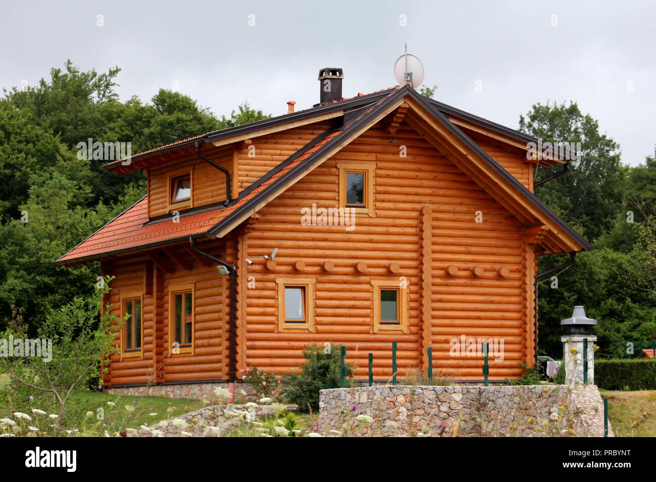 Cabane en bois nouvellement construit maison avec de petites fenêtres, nouvelle toiture tuiles, gouttière et sur le dessus de l'antenne satellite entouré d'herbe non coupée, petites fleurs Banque D'Images