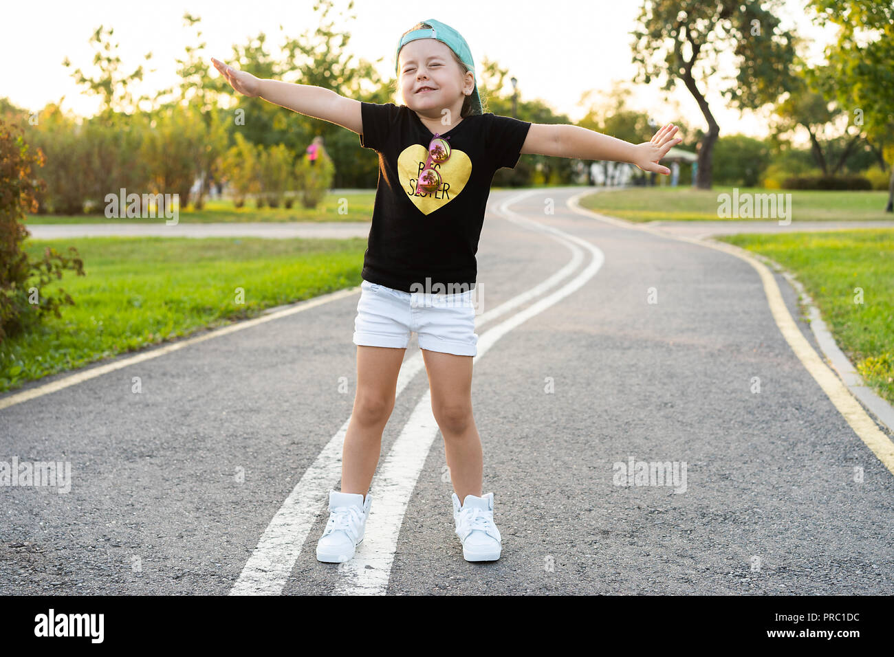 Fashion kid concept - portrait de petite fille mignonne enfant élégante portant une casquette à l'extérieur de la ville. Banque D'Images
