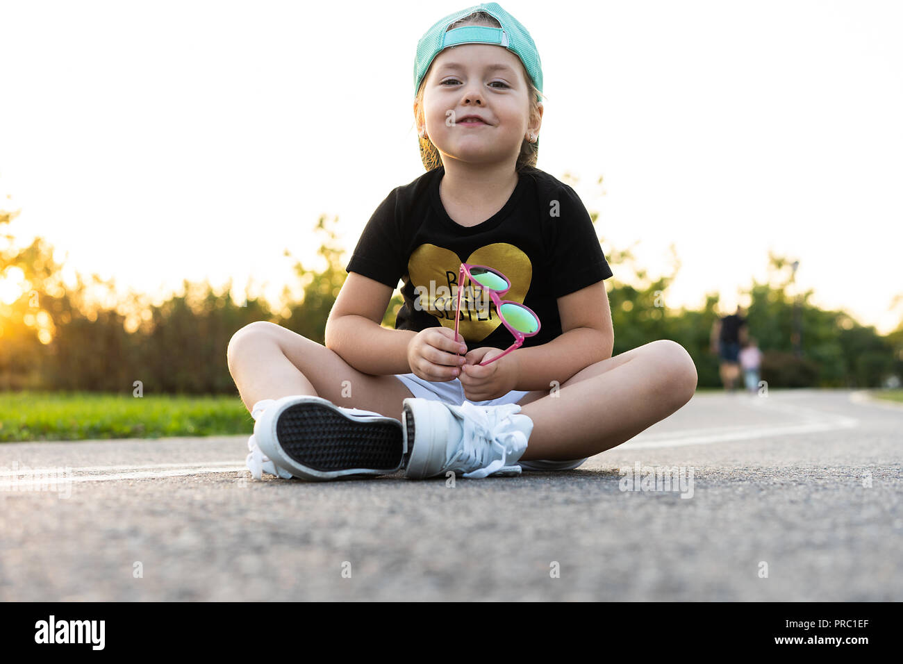 Petite fille mode enfant portant une casquette et t-shirt assis dans la  ville Photo Stock - Alamy