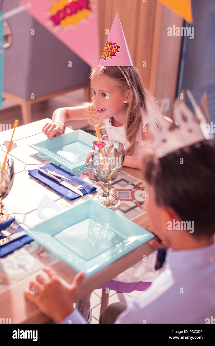 Curieux anniversaire girl smiling et d'attente pour l'alimentation à la fête Banque D'Images
