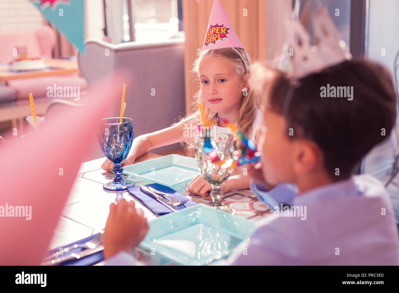 Anniversaire réfléchie girl wearing party hat et à la recherche à la table Banque D'Images