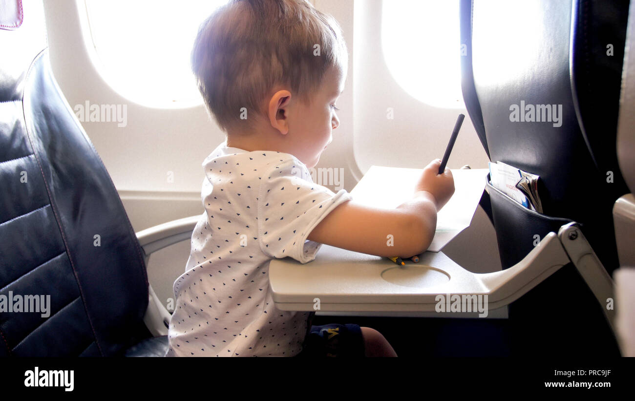 Photo de ton mignon bébé garçon dessin dans cahier pendant le vol en avion  Photo Stock - Alamy