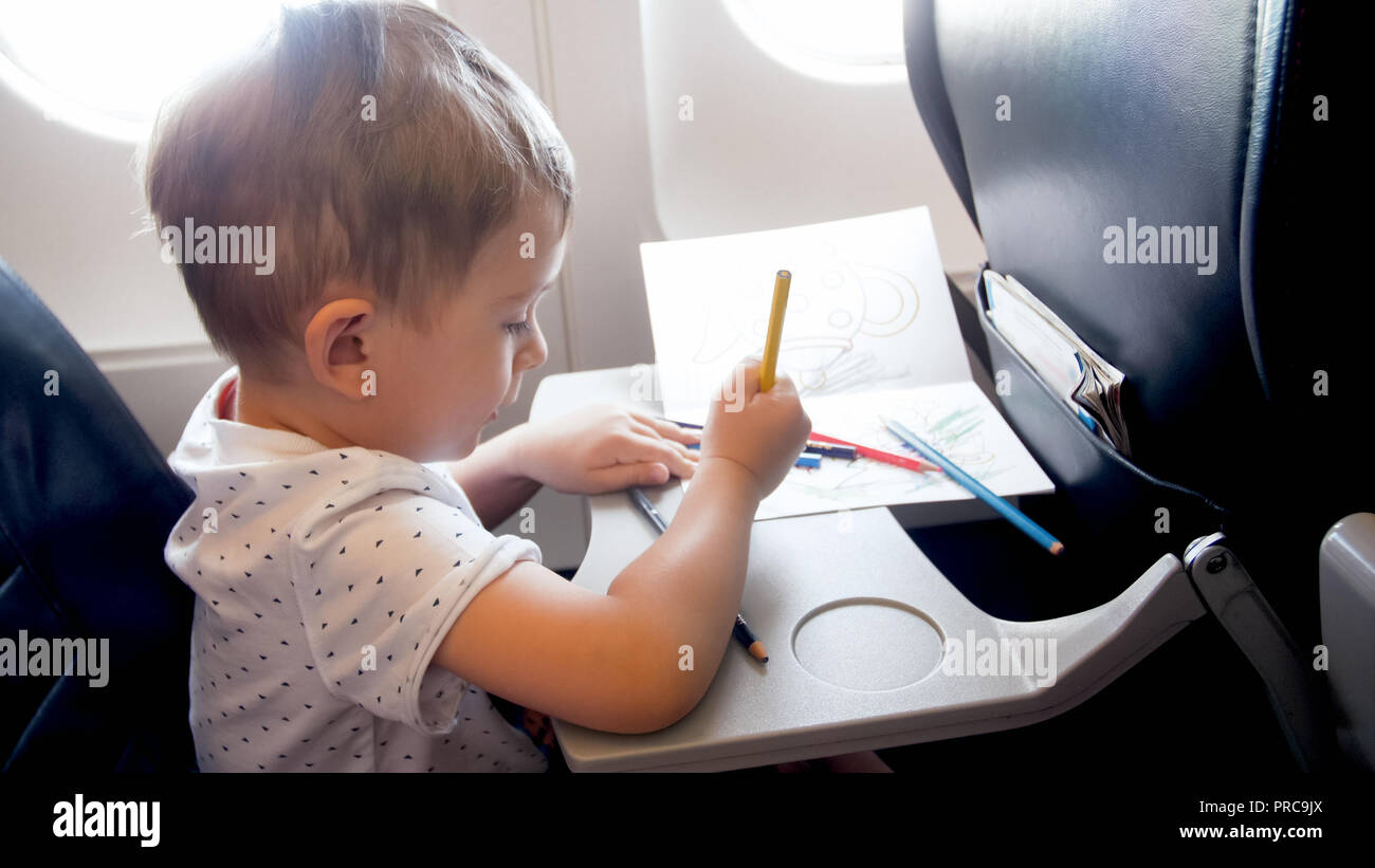 Portrait de ton petit garçon qui voyagent en avion et le dessin avec crayons pendant long vol Banque D'Images