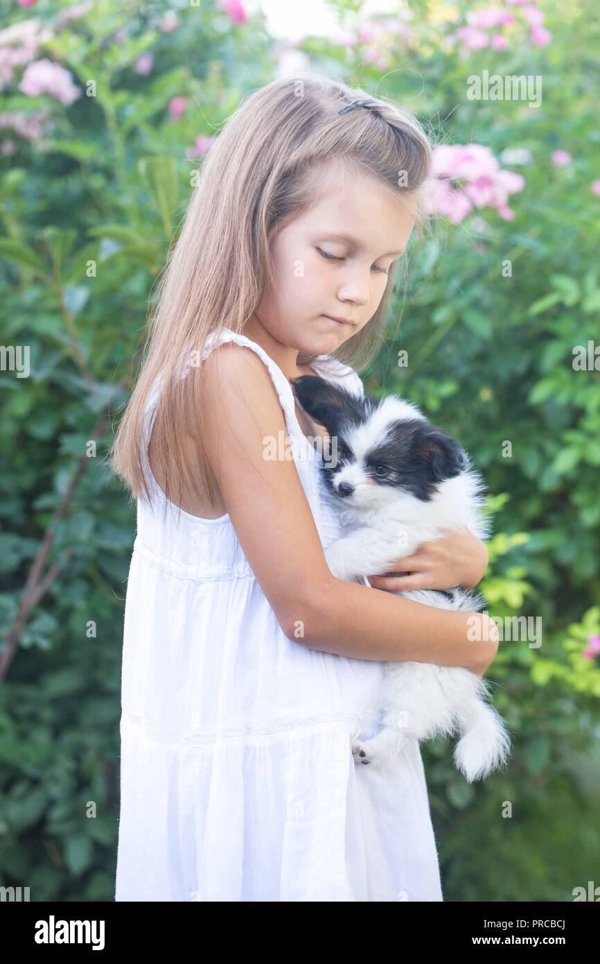 Petite fille tenant un chiot dans ses bras dans le jardin Banque D'Images