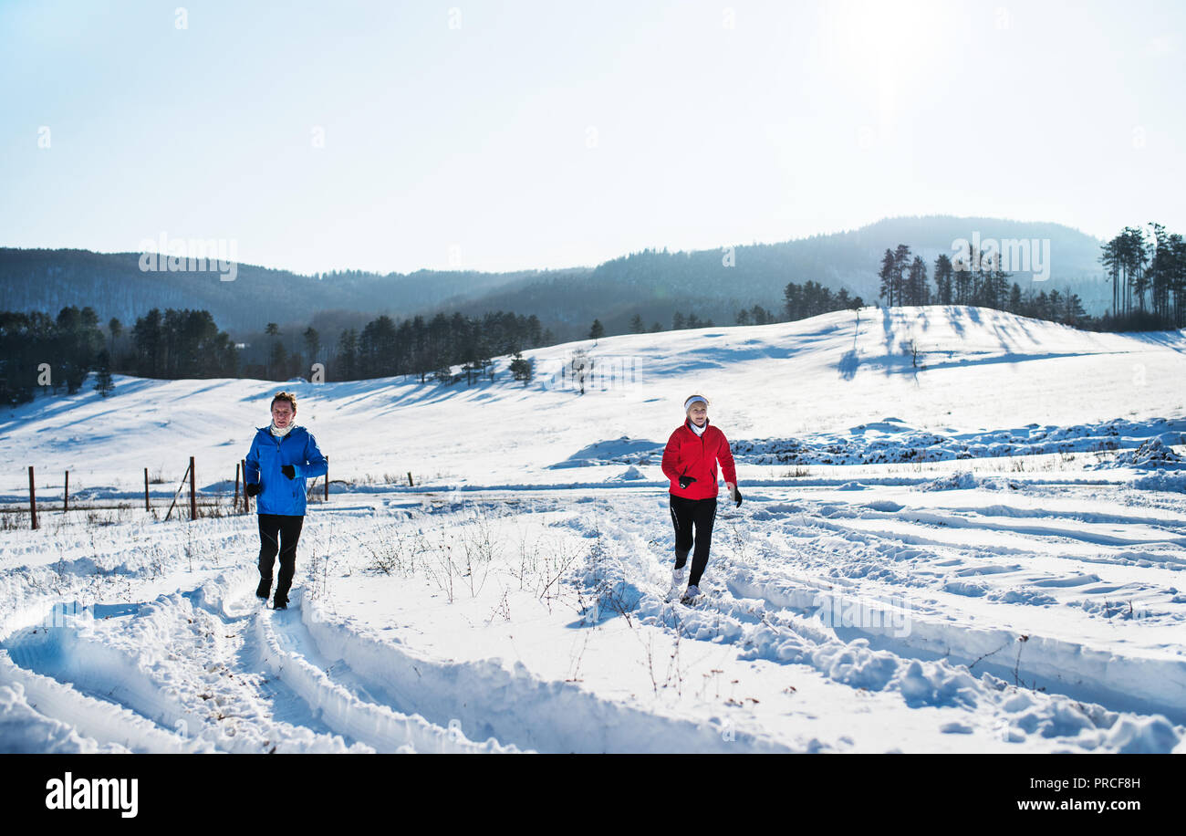 Une vue de face du couple jogging en hiver neige la nature. Banque D'Images