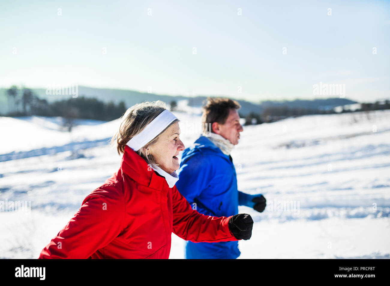 La vue latérale d'un senior couple jogging en hiver neige la nature. Banque D'Images