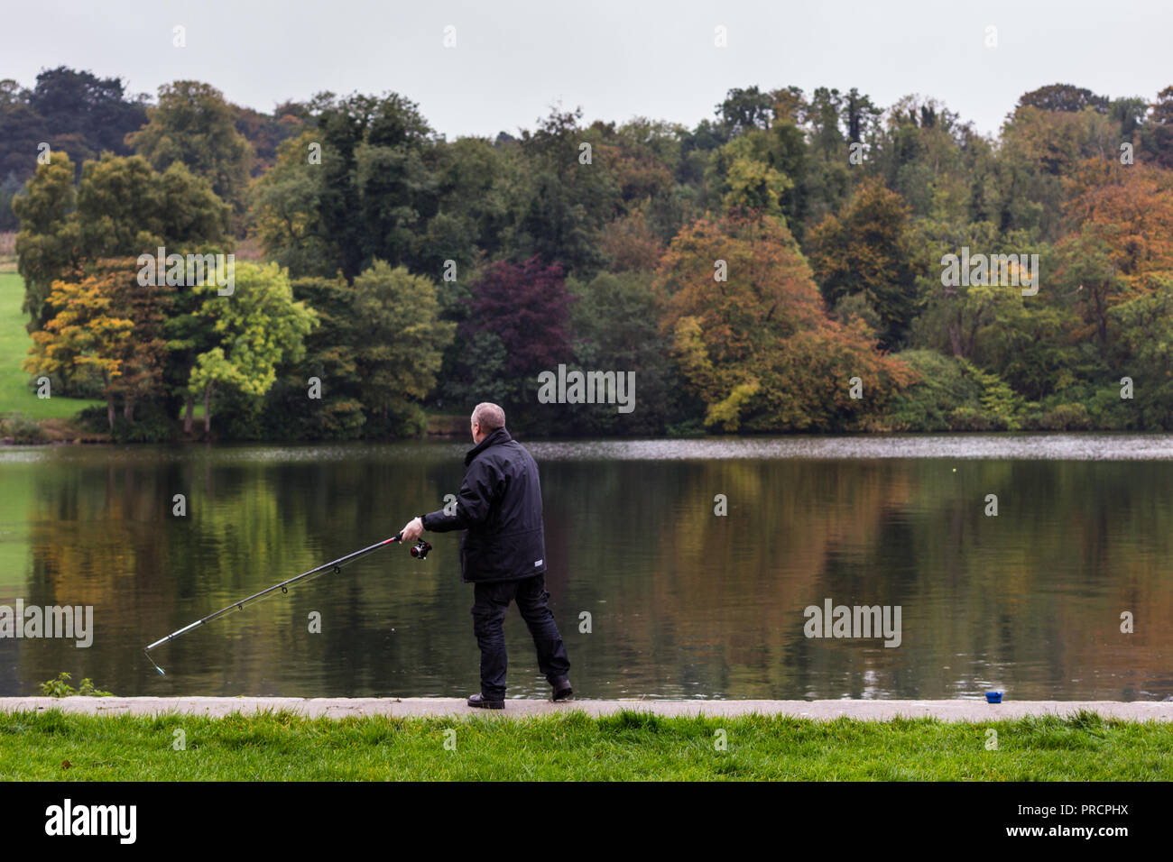 Un pêcheur au sujet de la ligne de pêche dans le lac. Castlewellan Forest Park, N.Ireland. Banque D'Images