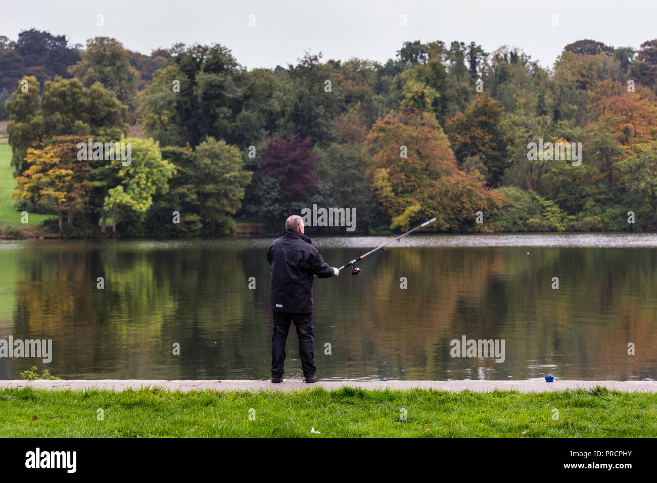 Un pêcheur casting son fil de pêche dans le lac. Castlewellan Forest Park, N.Ireland. Banque D'Images