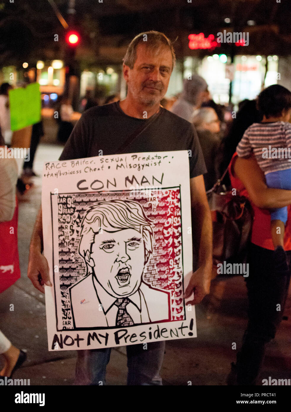 Un homme porte un écriteau 'con man, pas mon président' au cours d'une manifestation au centre-ville d'Oakland contre l'élection de Donald Trump, le 9 novembre 2016. Banque D'Images