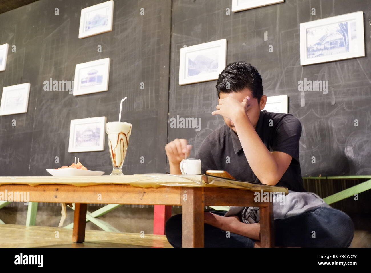 Les hommes seuls dans le café tout en regardant la pensée à un smartphone Banque D'Images