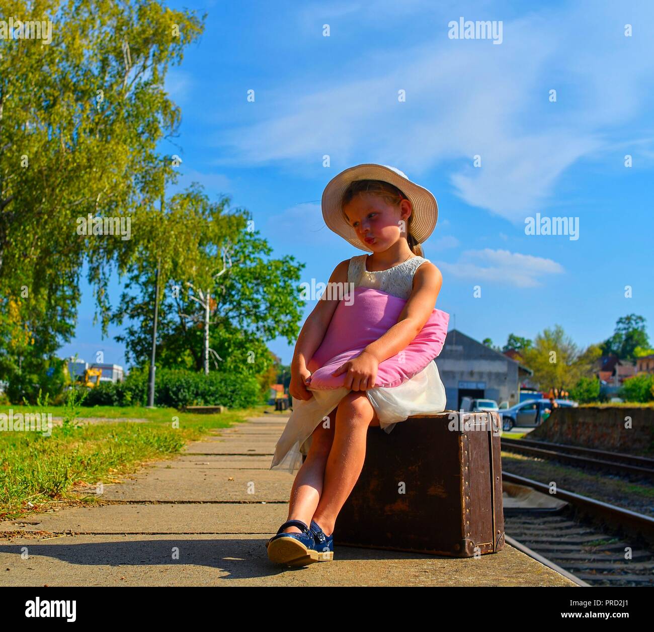 Cute girl holding peluche sur une gare, attendant le train avec vintage suitcase. Les voyages, vacances et enfance concept. 09/12/2012 10 voyages Banque D'Images