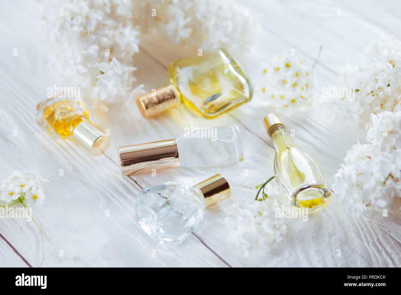 Flacons de parfum avec des fleurs blanches sur fond de bois Banque D'Images