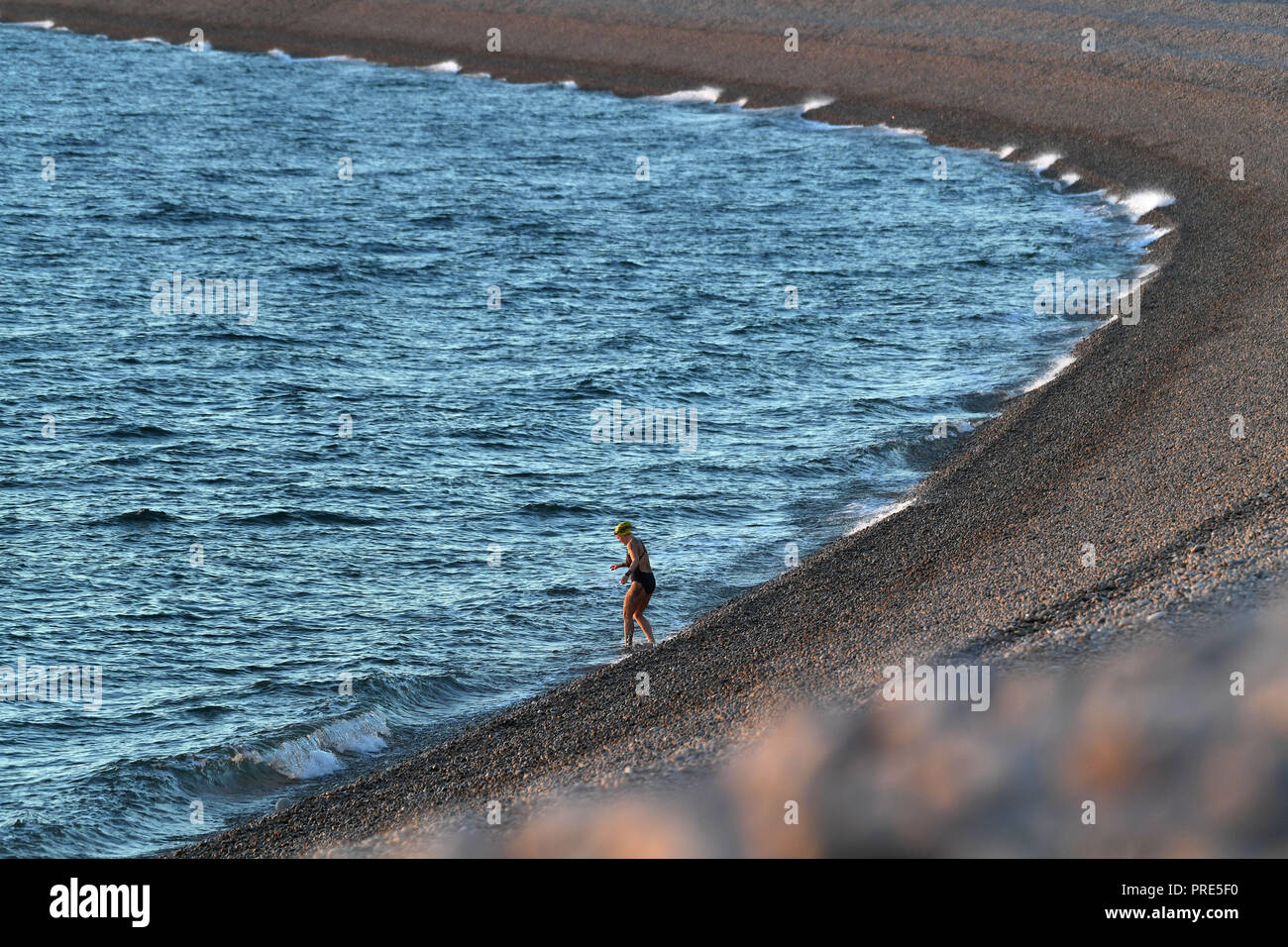 Portland, Dorset, UK. 1 octobre, 2018. Coucher de soleil sur la plage de Chesil à Portland, dans le Dorset, un nageur prend à la mer au coucher du soleil sur la plage de Chesil, Portland, Dorset Crédit : Finnbarr Webster/Alamy Live News Banque D'Images