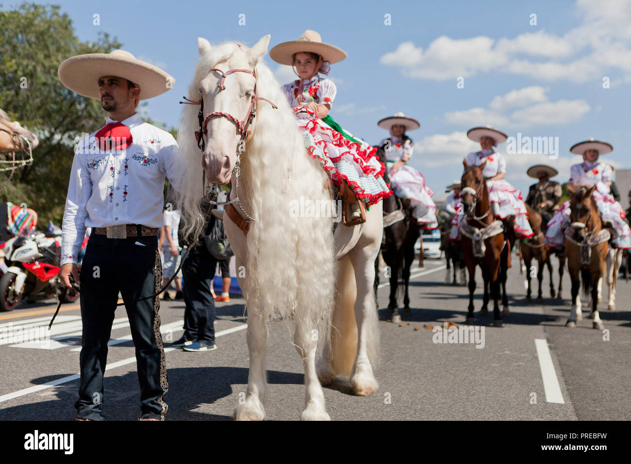Cowgirl mexicain (charras) sur un Cremello cheval blanc (aka blue-eyed crème) avec les cheveux longs (long mane) - USA Banque D'Images