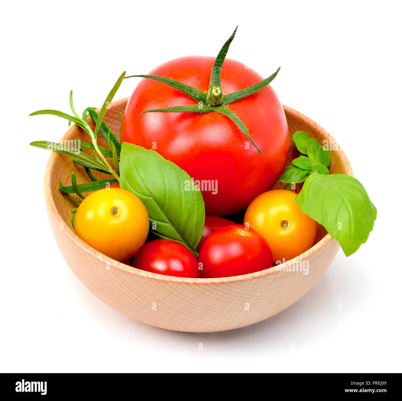 De délicieuses tomates fraîches et fines herbes dans un bol en bois. Close up shot, isolé sur fond blanc. La gastronomie ou l'alimentation saine. Banque D'Images
