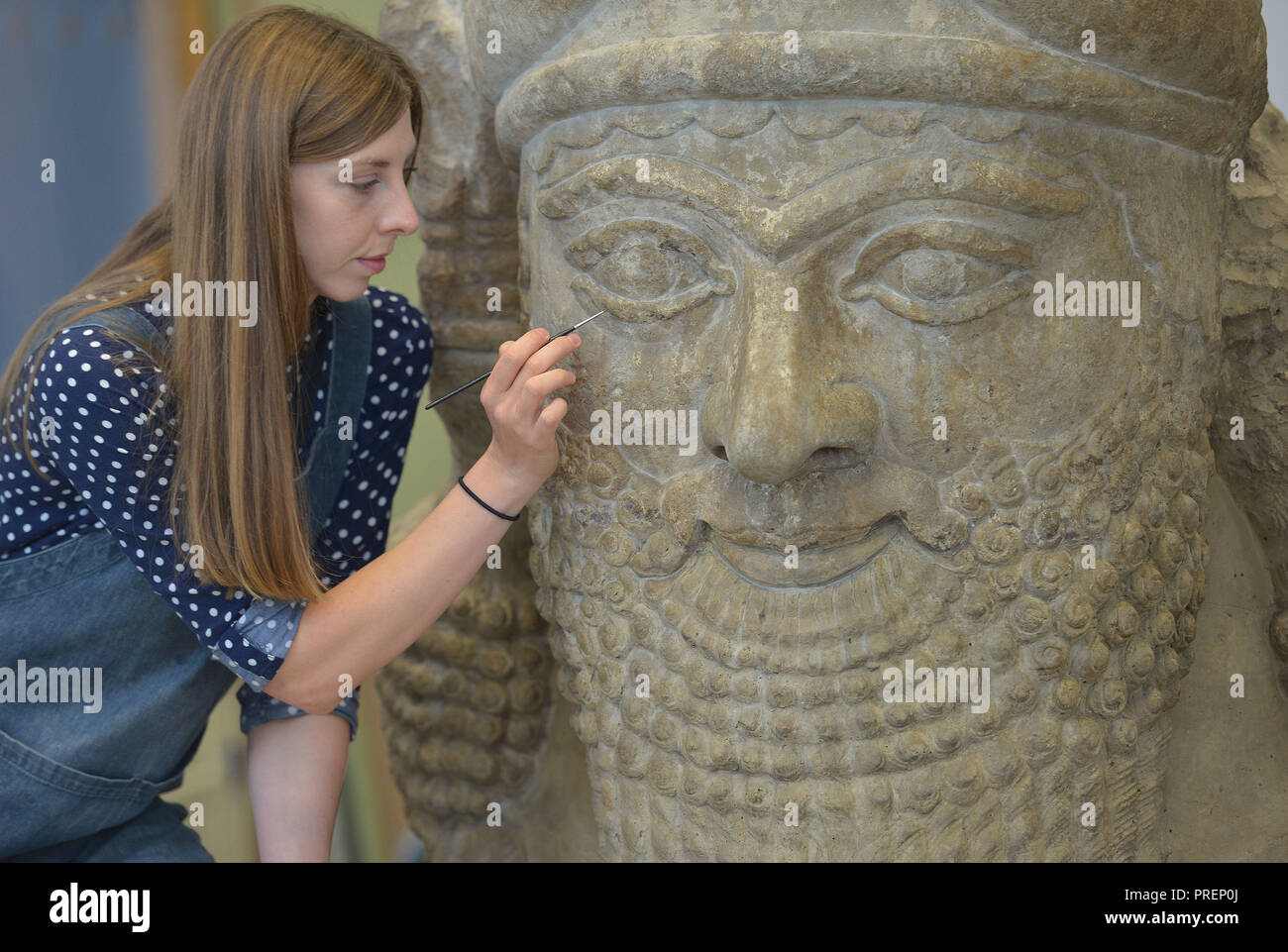 British Museum restaurateur pierre Kasia Weglowska, prépare une tête d'un taureau ailé assyrien, du palais d'Assurbanipal, le père d'Ésar Haddon,, à Nimrud 670BC. La tête pesant 1,8 tonnes fait partie de la la mise en service pour le JE SUIS Assurbanipal : roi du monde, roi d'Assyrie, exposition au British Museum, Londres, qui s'ouvre le 8 novembre 2018. Banque D'Images