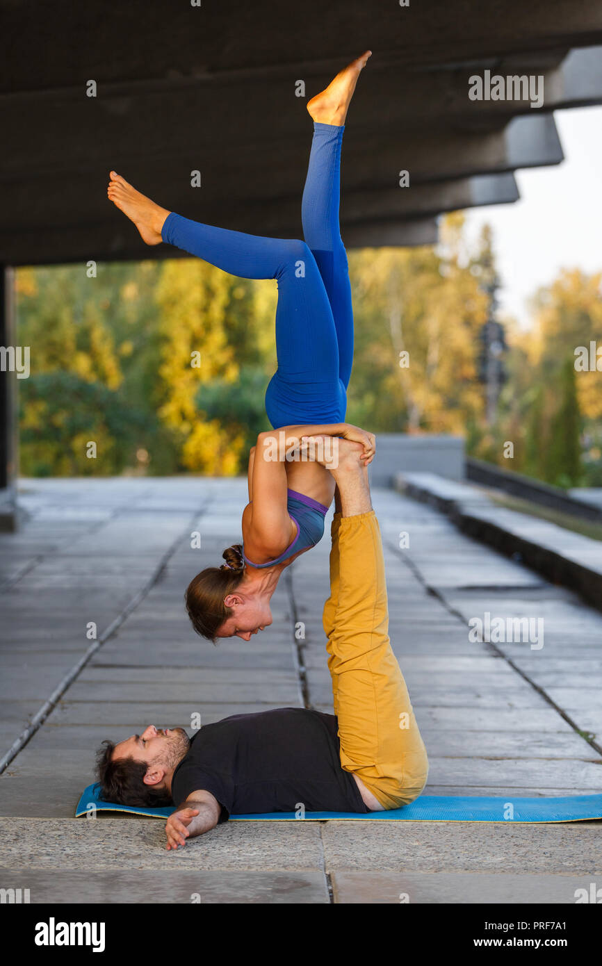 Jeune homme et girl practicing yoga acro en ville sur la rue Banque D'Images