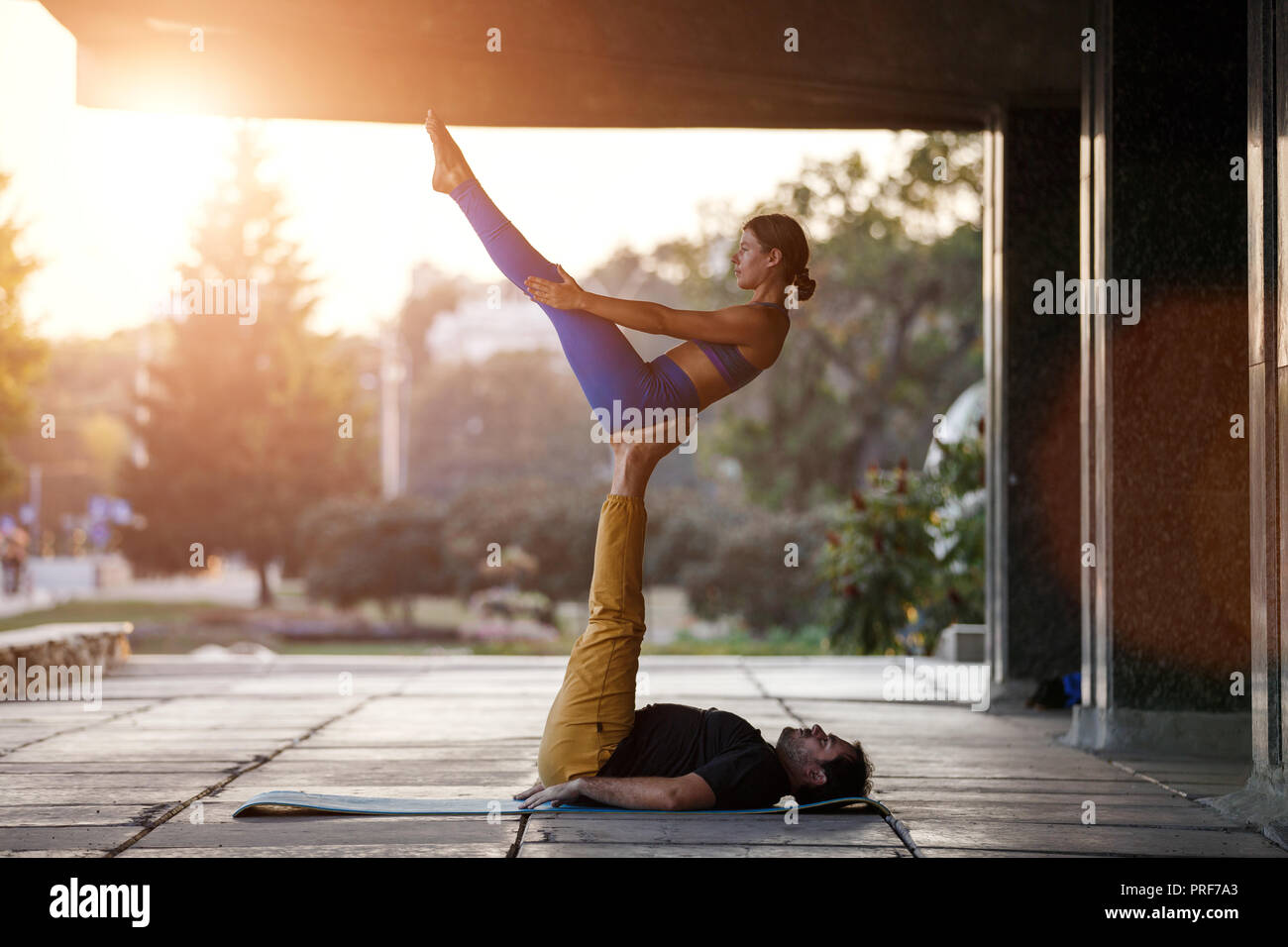 Jeune homme et girl practicing yoga acro en ville sur la rue Banque D'Images