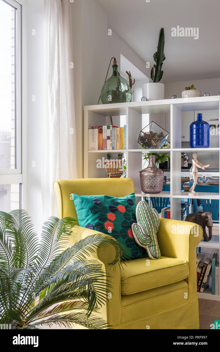 Nouveauté coussins sur fauteuil jaune avec étagère en appartement à Londres Banque D'Images