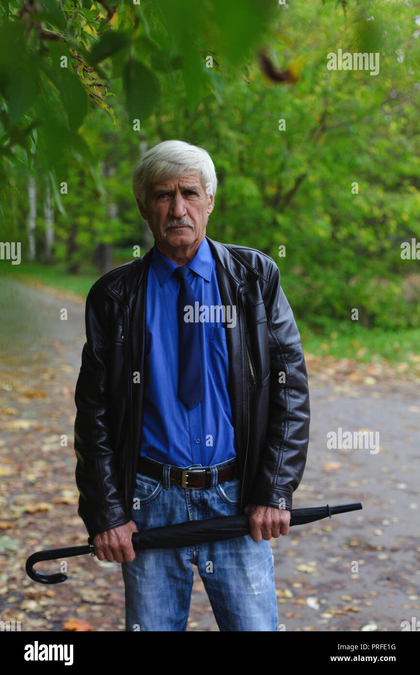 Homme aux cheveux gris avec un parapluie dans les mains sur la rue. Un homme est de 60 ans. Banque D'Images