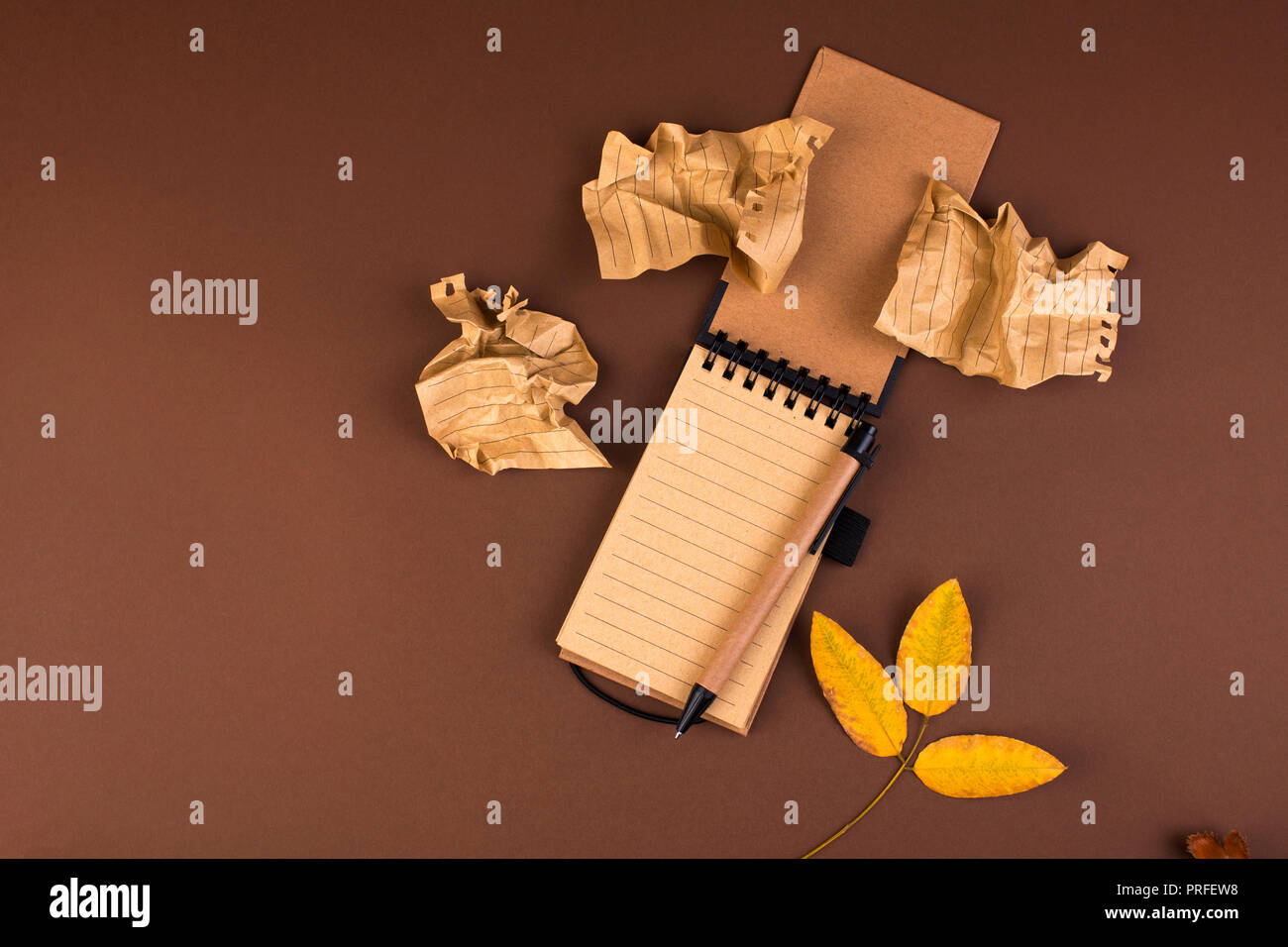 Un ordinateur portable ouvert des registres et de feuilles froissées sur un fond brun. Office de la planification. Espace libre pour le texte. Atmosphère d'automne et des feuilles jaunes. Haut Banque D'Images